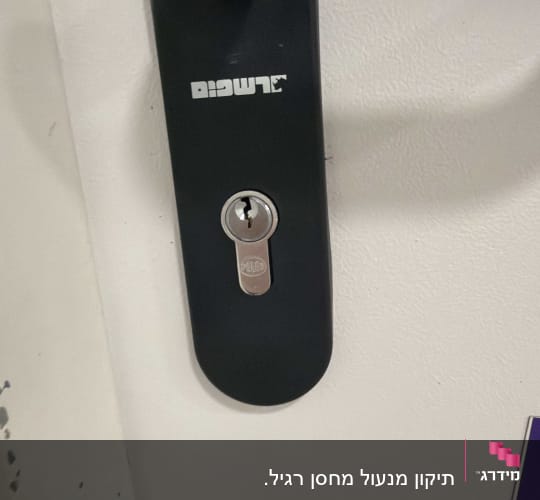 מנעול מותקן על דלת לבנה עם ידית שחורה